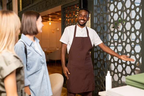 Smiling waiter seating customers in cafe