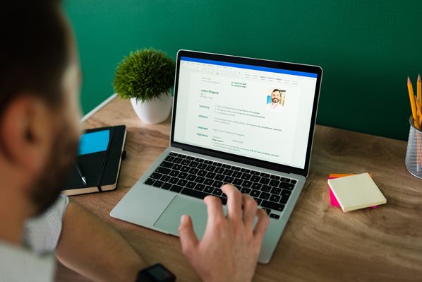 Man typing his CV on a laptop