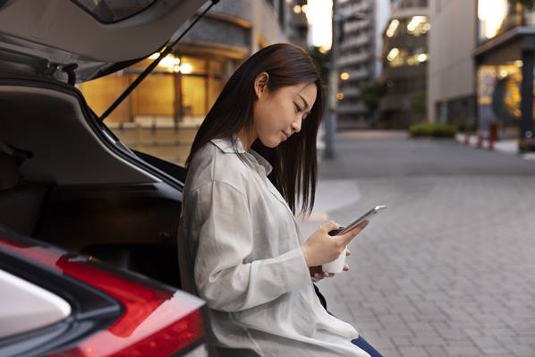 Women reading text leaning on car